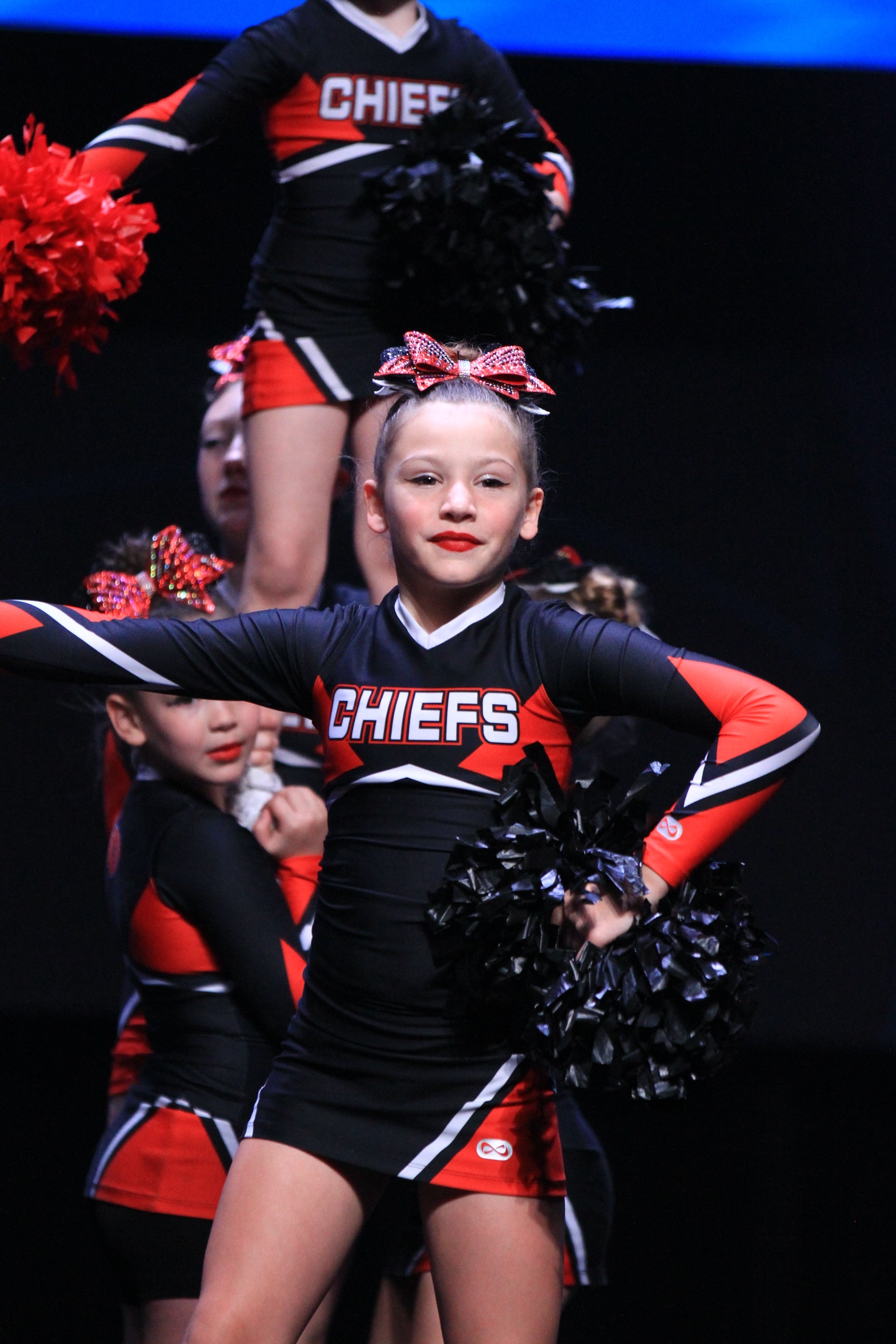 Cheerleader girl in black dress performing on stage