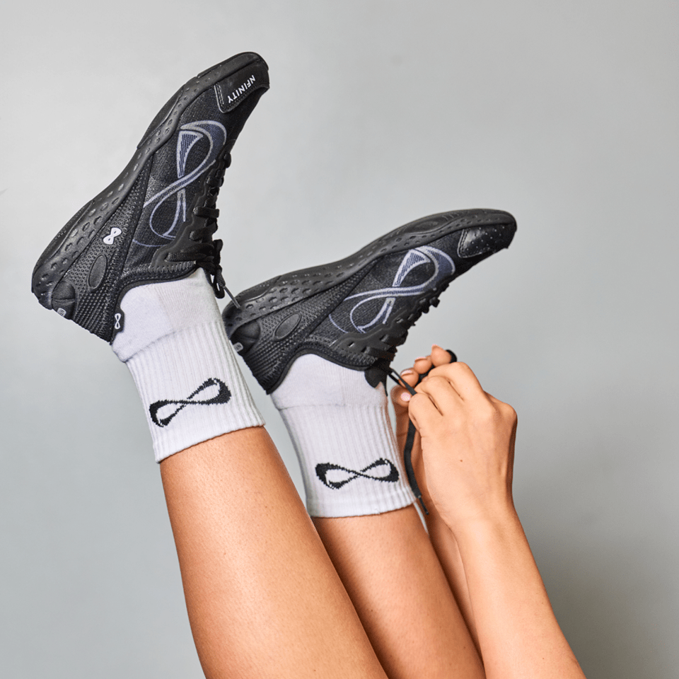 Cheerleader with legs raised wearing black Nfinity Alpha cheer shoes