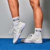 Cheerleader standing on a blue mat in white Nfinity Evolution cheer shoes
