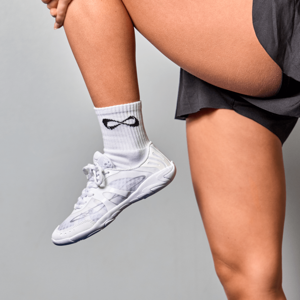 Close-up of white Nfinity Vengeance cheer shoes mid-step with Nfinity socks